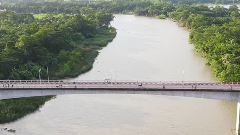 aerial follow motorbike crossing bridge, nature landscape, river and forest background