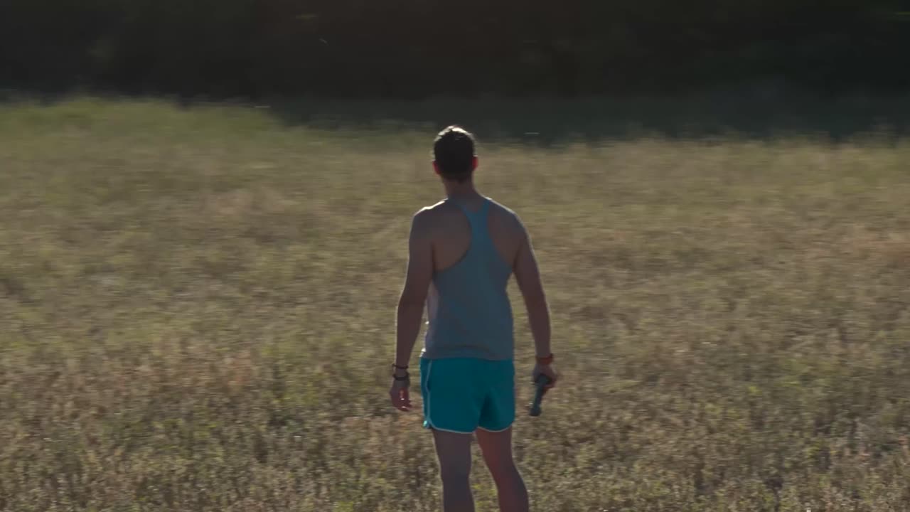 포도 ⁇ 에 있는 근육이 튼튼한 남자,  ⁇ 은 일몰에 그의 주위를 빠르게 돌고 그는 그의 드론을 제어합니다