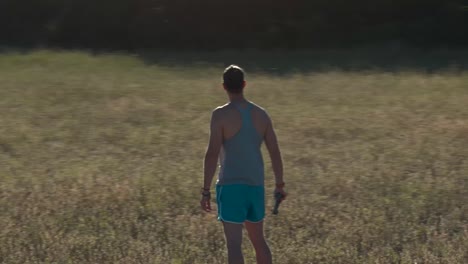 muscular man in a vineyard, the shot turns quickly around him on a sunset and he controls his drone