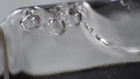 macro shot of clear liquid with few bubbles on the surface slowly moving in reagent tube