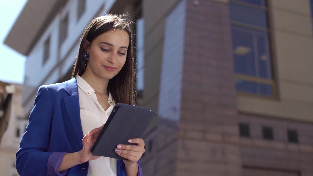 Jovem empresária sorrindo enquanto usa um tablet ao ar livre