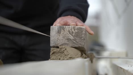 cropped view of a mason laying brick on construction site