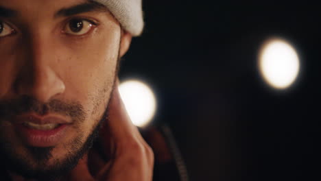 close up portrait attractive young hispanic man on rooftop at night smiling happy looking confident enjoying urban nightlife with lights in background