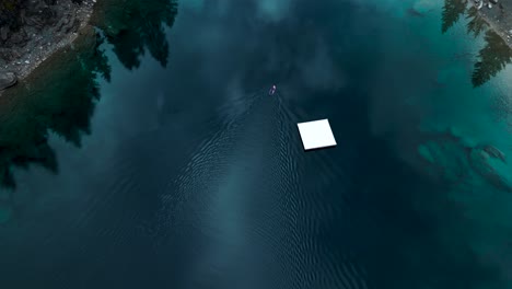 aerial view of a man in a neopren swimming on a board in a pritine blue water lake caumasee in switzerland