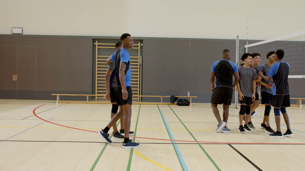Afro-Amerikaanse mannelijke spelers schudden handen en omhelzen elkaar onder het net op een schoolveld, wat het einde van de wedstrijd markeert.