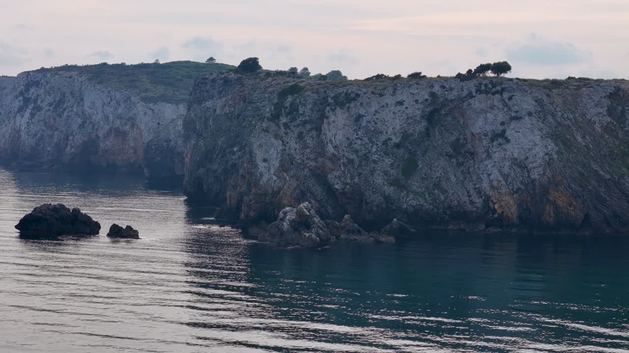 Veduta aerea rotante sopra scogliere frastagliate e una costa aspra sull'isola di Evia, Grecia.