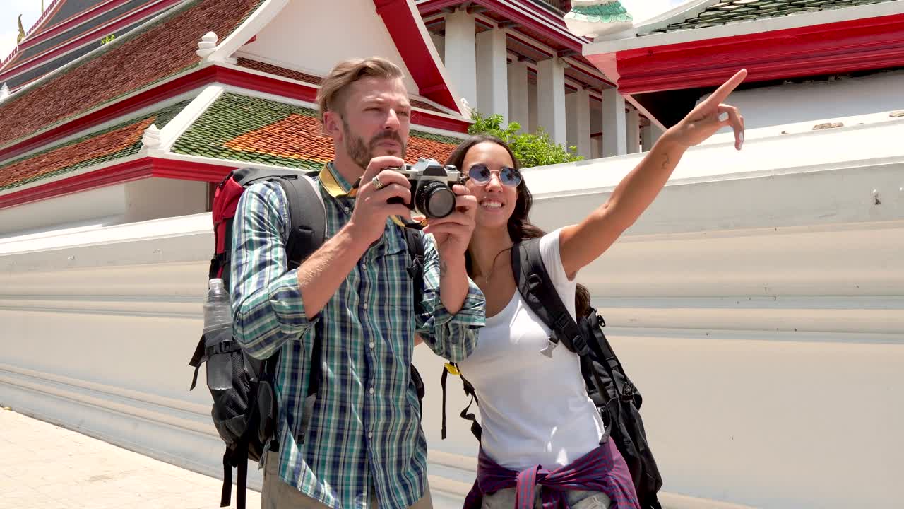 una pareja de turistas de mochila tomando fotos en un templo tailandés en tailandia