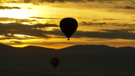 telefoto aéreo disparado alrededor de un globo de aire caliente con un dramático fondo de amanecer