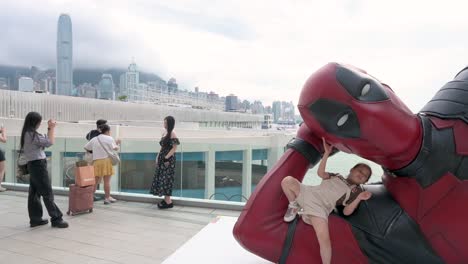 in hong kong, a child is seen posing with an 8-meter deadpool figure as crowds capture the moment. the installation promotes disney's "deadpool and wolverine" film.