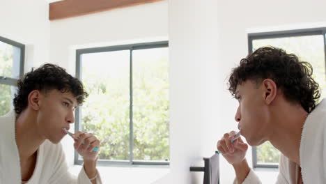 brushing teeth in bathroom, person looking in mirror, morning routine at home