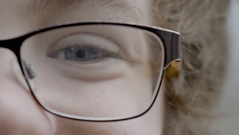 closeup on a young boy's blue eye and eyelashes with glasses while smiling