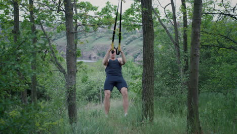 man doing suspension training in a forest