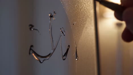 hand drawing an anchor on a misted window