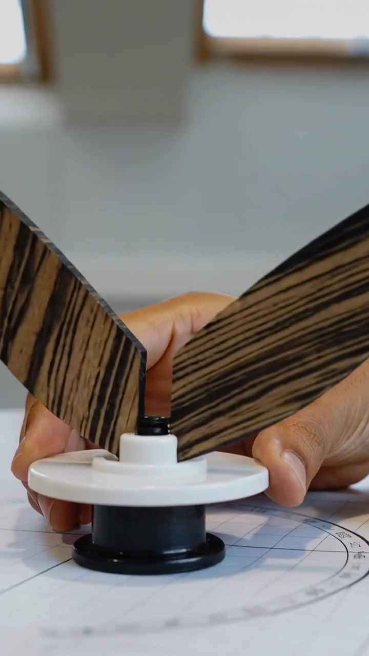 Video verticale: Due mani che allineano e inseriscono pale a strisce in un mozzo su una scrivania, guidando il movimento.