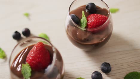 video of chocolate pudding with strawberries and bluberries on a wooden surface