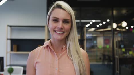 Caucasian-businesswoman-walking-looking-at-camera-and-smiling-in-modern-office