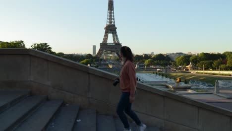 joven mujer atractiva subiendo escaleras en el trocadero con la torre eiffel en el fondo durante la mañana de verano temprano