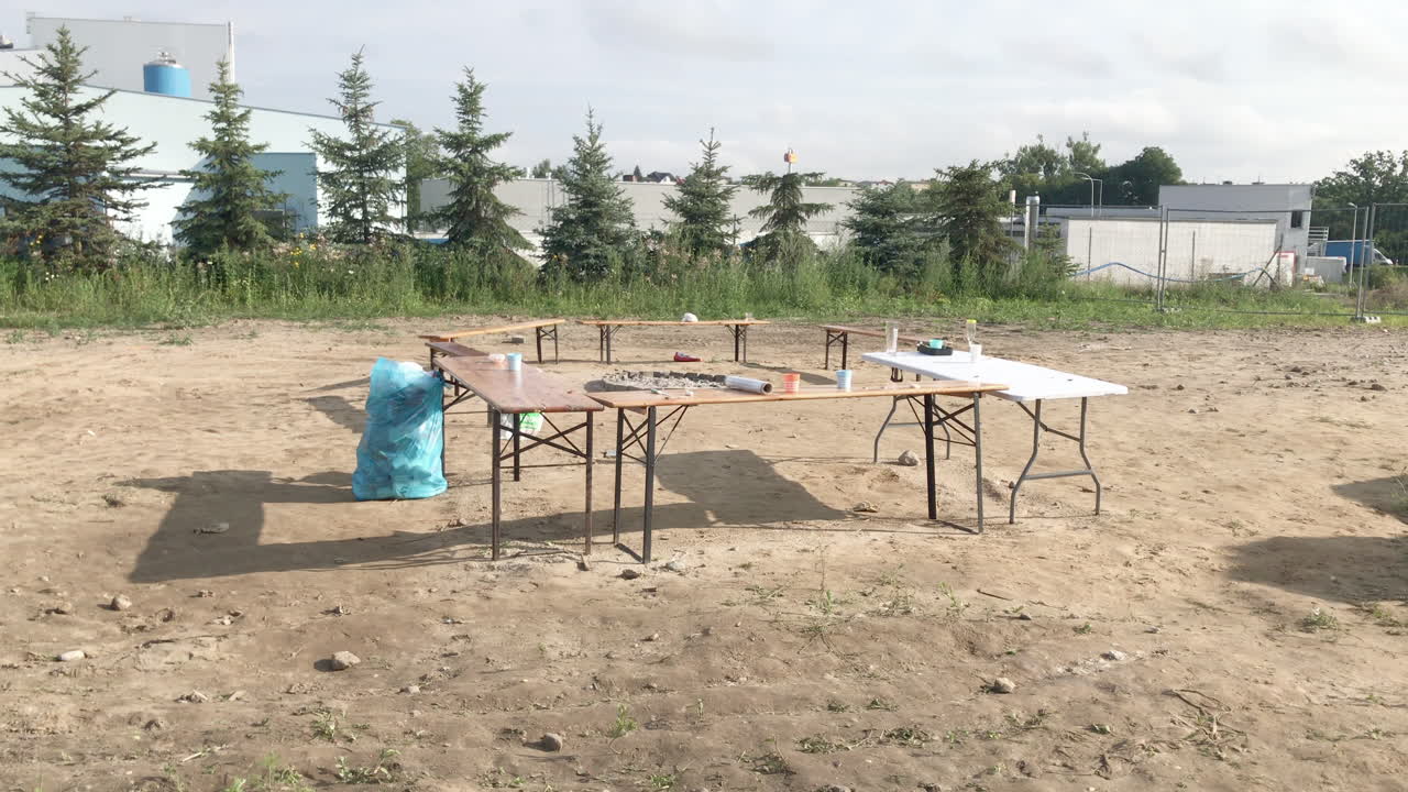 Empty tables after the party stand in the courtyard, other garbage collected in the bag, free space on the sand, waste segregation