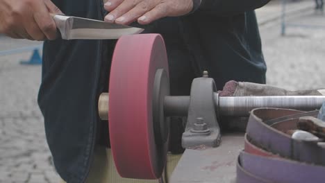 man sharpening a knife on a grinding wheel