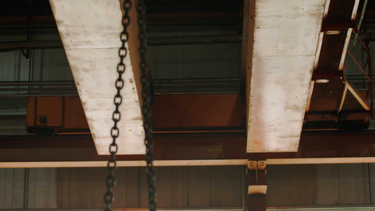 Ripresa in movimento di una gru a soffitto che solleva materiali di produzione.
