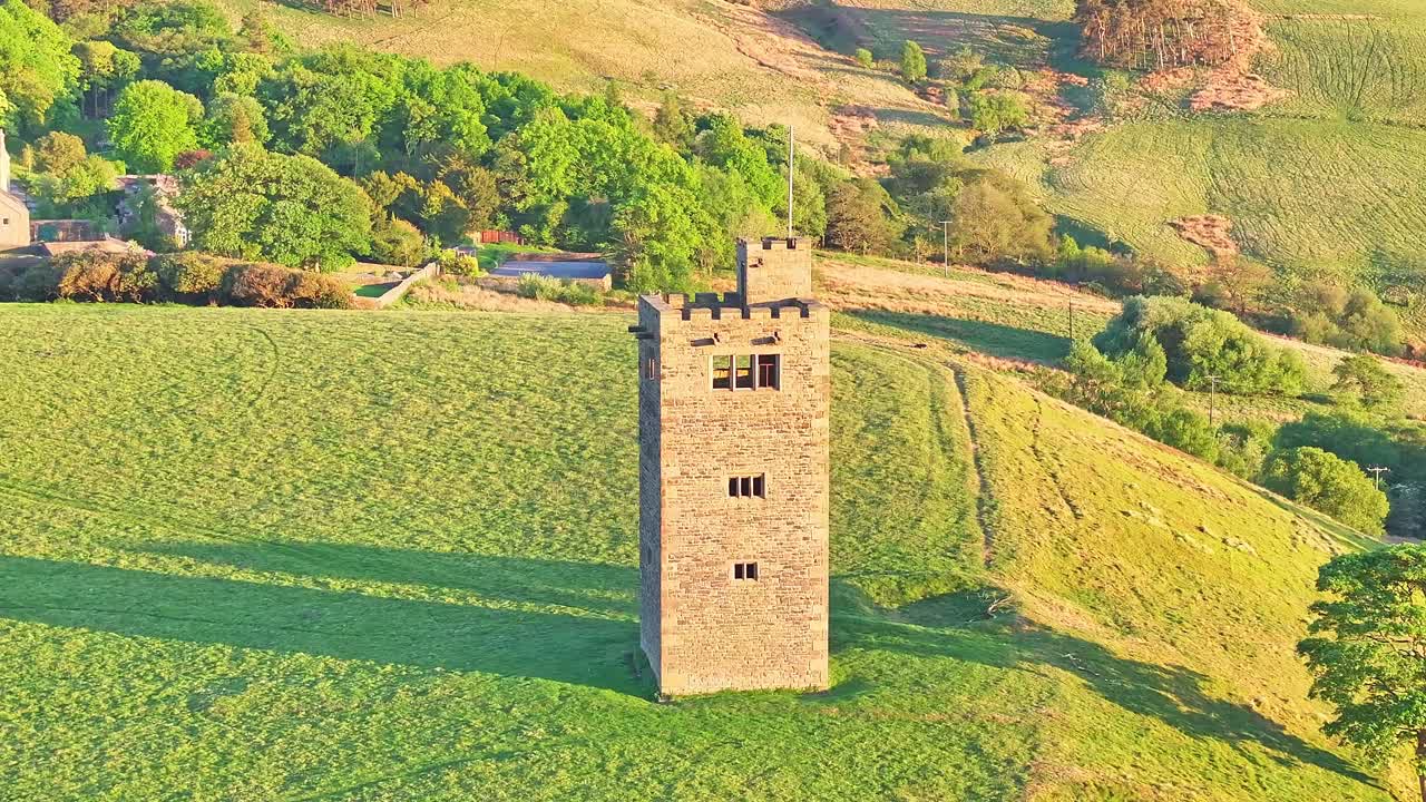 Aerial: Boot's Folly ancient tower at sunset close to Strines Reservoir near Sheffield, South Yorkshire, England, push in drone shot