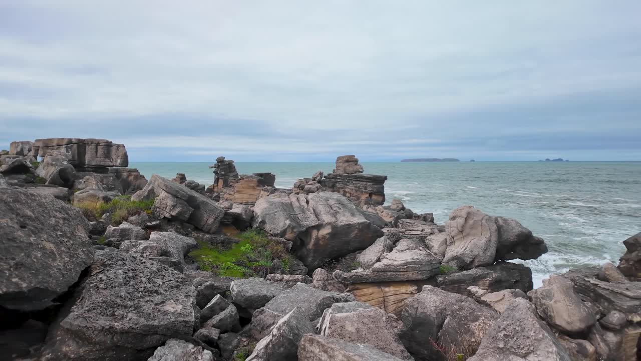 Filmisk langsom panorering hen over de barske kystklipper ved Peniche, Portugal, med turkisblåt Atlanterhavsvand, brusende bølger og dramatiske skyfulde himmel.