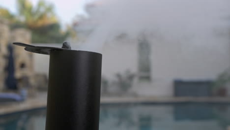 backyard bbq pit smoke stack with smoke coming out in front of pool close up