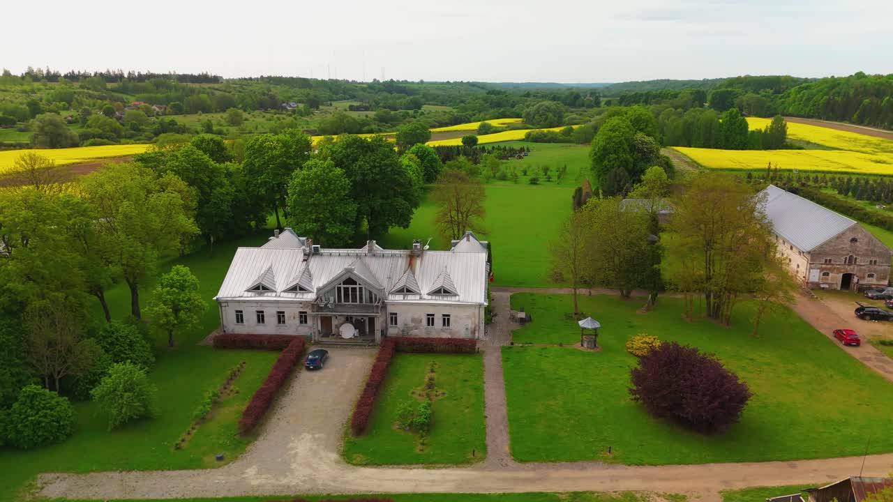 Aerial view of Babtyno Manor, a historic estate surrounded by lush greenery, featuring classic architecture and a well-kept garden. themes related to history, heritage, and countryside estates.
