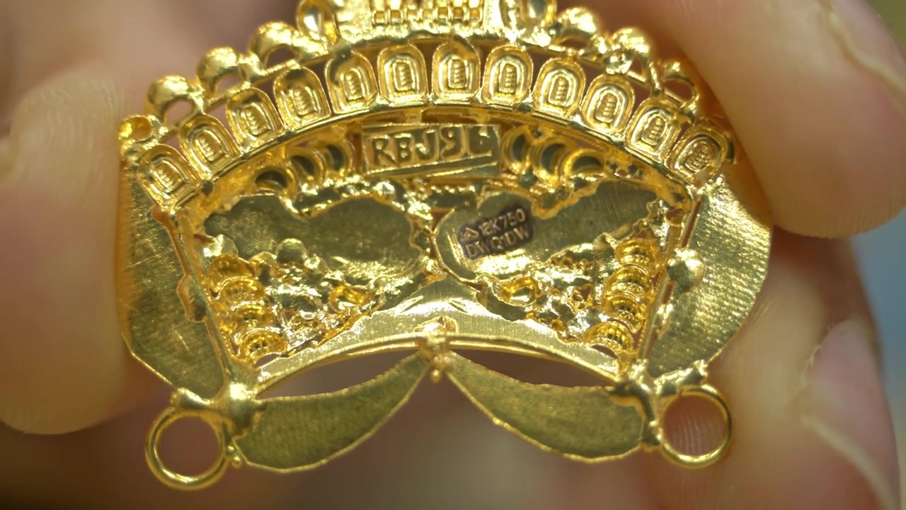Dettagli di gioielli in oro 18k 750 con identificazione unica del punzone (HUID), ciondolo in oro puro in un negozio, primo piano.