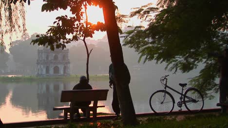 la gente se sienta en un parque en hanoi al atardecer y admira la vista