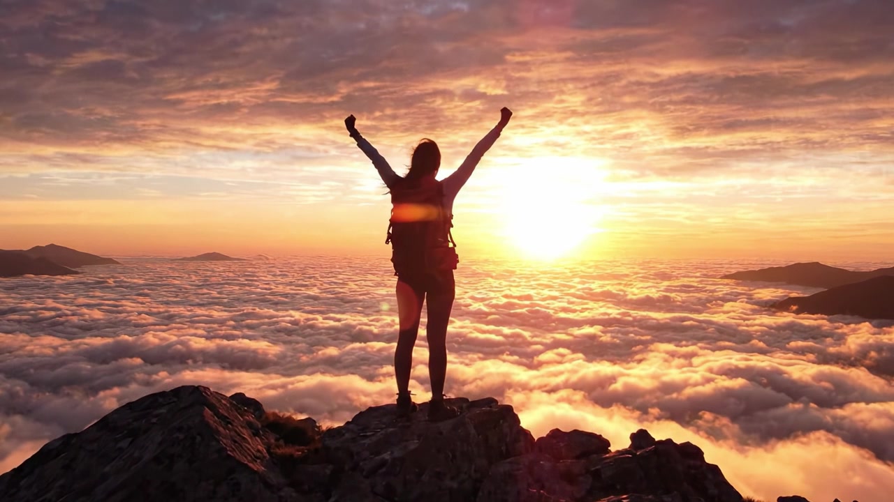 Un viaje hacia la libertad: Una silueta al atardecer en la cima de una montaña celebrando la belleza de la naturaleza y los logros sobre las nubes