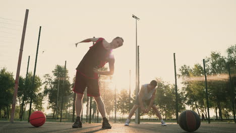 Jugadores-De-Baloncesto-Masculinos-Concentrados-Que-Se-Extienden-En-La-Cancha-De-Baloncesto-Al-Aire-Libre-1