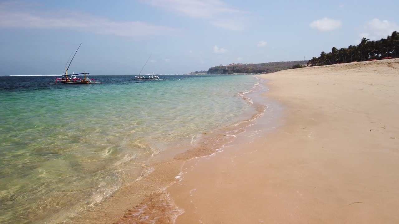 Passeggiando sulla spiaggia più incredibile di Nusa Dua. Destinazione da sogno per i viaggiatori con oceano blu, splendido ambiente tropicale, sabbia dorata e palme.