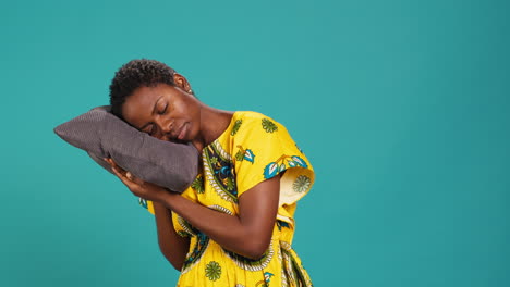 Sleepy-young-adult-taking-a-nap-on-a-grey-pillow-in-studio