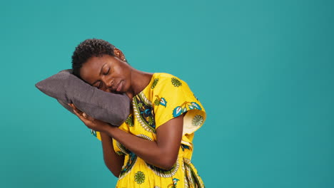 sleepy young adult taking a nap on a grey pillow in studio