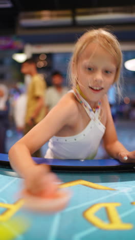 young girl enjoying a game of air hockey at the arcade