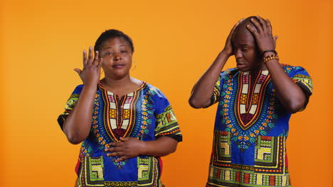 stressed man and woman dealing with headache in studio