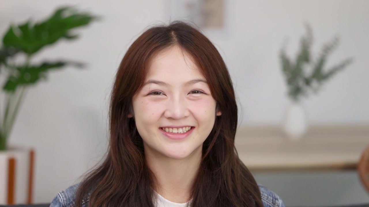 หญิงสาวชาวเอเชียผู้มีความสุขกำลังยิ้มและทำท่าโอเค
