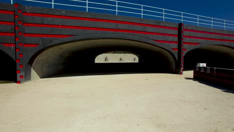 bicyclist in a line ride by underpass opening at indian bend wash and flood control area, indian bend park and wash, scottsdale, arizona