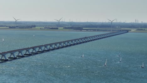 long lens drone shot of the zeeland bridge showing sailboats and a big port in the background