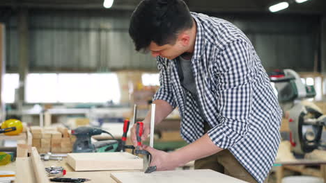 woodworker using clamps on wood pieces in workshop