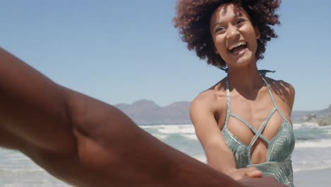 woman holding man hand and running on beach in the sunshine 4k