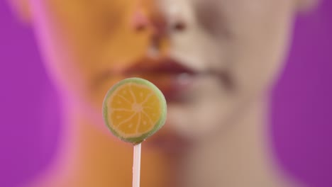 mujer lamendo helado con seducción, boca en primer plano en fondo púrpura