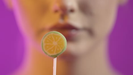 woman licking popsicle with seduction, mouth close-up shot on purple background