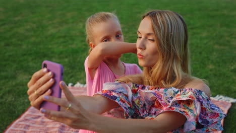 madre e hija haciendo el tonto en meadow. familia tomando selfies en el parque de la ciudad.