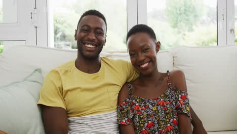 Porträt-Eines-Glücklichen-Afroamerikanischen-Paares,-Das-Auf-Dem-Sofa-Sitzt-Und-Sich-Umarmt-Und-In-Die-Kamera-Lächelt