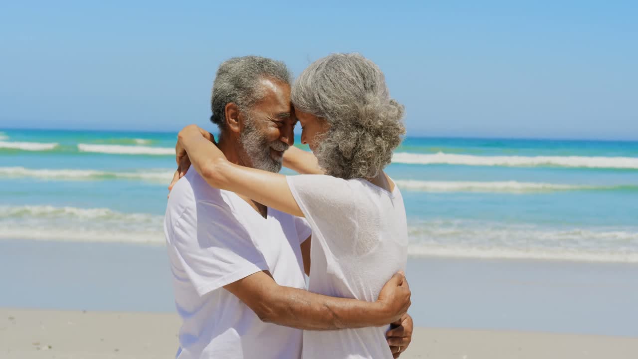 Side view of happy active senior African American couple embracing each other on the beach 4k