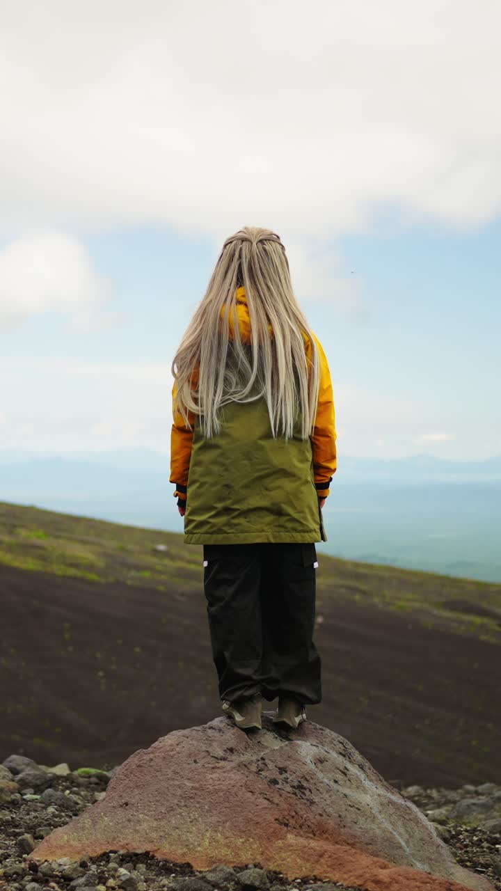 Woman Standing on a Rocky Outcrop Overlooking a Volcanic Landscape