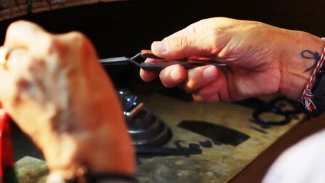 Close-up-of-Craftswoman-blowing-a-torch-to-shape-metal