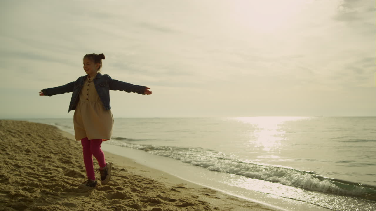 niña pequeña bailando en la playa al atardecer. niña feliz jugando sola al aire libre.